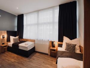 1 Schlafzimmer mit 2 Betten und einem Fenster mit einer Badewanne in der Unterkunft MiDoma, Self Check-In Hotel, Hannover Messe in Hannover