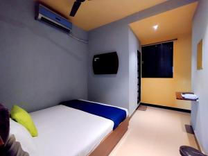 um pequeno quarto com uma cama e uma televisão em Hotel Aspen - Near International Airport em Mumbai