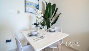 a white dining room table with white chairs and flowers at RARE Holiday Homes welcomes you in a studio apartment - lake view - Near mall - RCTA 910 in Dubai