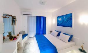 a white and blue bedroom with a large bed at Mojito Beach Rooms in Lakhania