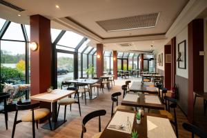 卡斯特乌Hotel & Aparthotel Casteau Resort Mons Soignies的一家有桌椅和窗户的餐厅