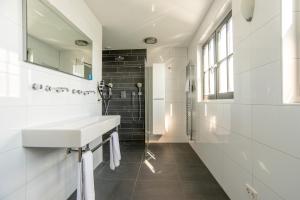 ein weißes Bad mit einem Waschbecken und einer Dusche in der Unterkunft Najade Resort in Loosdrecht