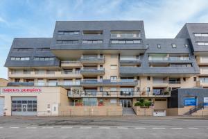 an apartment building with a gray roof at Un Balcon sur le Port - Place de parking in Courseulles-sur-Mer