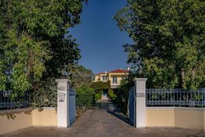 a gate to a mansion with a house in the background at Villa Elmar in Egina