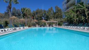 a large swimming pool with chairs and a building at Bayside Salgados in Albufeira
