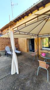 un patio con un grande ombrellone, sedie e tavoli di CASA ZORITAS a Antimio de Arriba