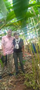 an older man and woman standing under a palm tree at Spice Villa Thekkady in Thekkady