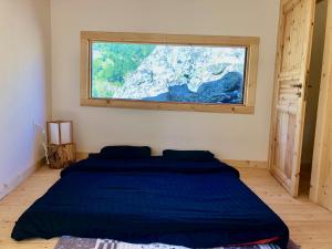 a bedroom with a blue bed with a large window at Cabin on a Rock - Mountain Escape in Deçan