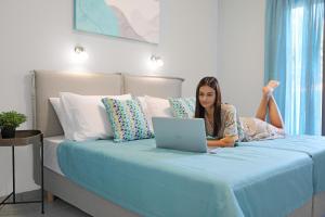Eine Frau, die mit einem Laptop auf einem Bett liegt. in der Unterkunft Drosia Villa Private Nature Getaway! in Plakias