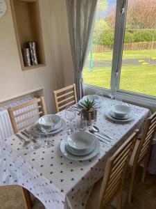 a table with plates and glasses on it with a window at Ocean View Sunbeach in Llwyngwril