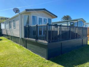 a mobile home with a deck on the grass at Ocean View Sunbeach in Llwyngwril