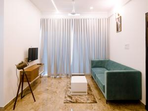 a living room with a green couch and a television at Avalon Homes in Perintalmanna