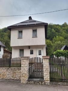 a white house behind a fence with a black roof at dar diyafa in Kreševo