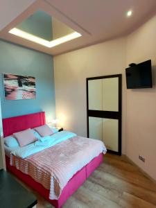 a bedroom with a pink bed and a flat screen tv at Mirror Pink Studio Apartment in Krakow