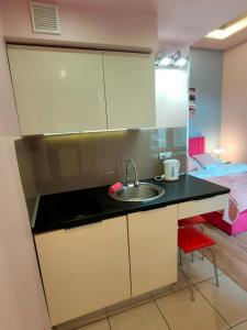 a small kitchen with a sink and a bed at Mirror Pink Studio Apartment in Krakow