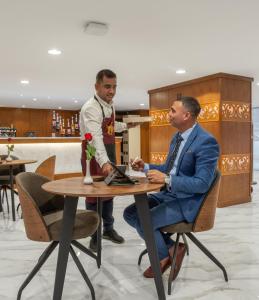 Zwei Männer sitzen an einem Tisch in einem Restaurant. in der Unterkunft فندق روز جدة 2 in Dschidda
