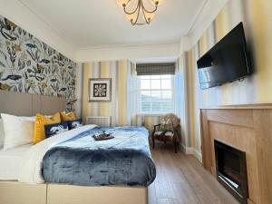 um quarto com uma cama, uma televisão e uma lareira em Atholl Arms Hotel Dunkeld em Dunkeld