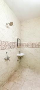 a white bathroom with a sink and a mirror at Hotel Tom International - Near Nizamuddin Railway Station in New Delhi