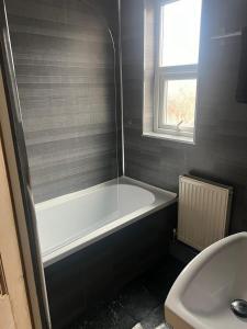 Jesmond Vale 3 Bedroom Apartment في نيوكاسل أبون تاين: حمام مع حوض استحمام ومغسلة