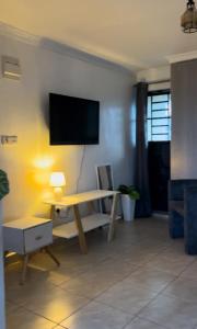 a living room with a table and a tv on a wall at Rooftop Studio Apartment - Mirema in Nairobi