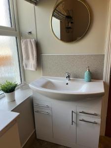 y baño con lavabo blanco y espejo. en Kingarrow Cottage, en Omagh