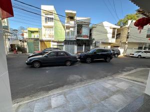 deux voitures garées dans une rue en face des bâtiments dans l'établissement MoTel HỒ XUÂN, à Pleiku