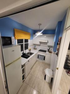 a small kitchen with white appliances and blue walls at Apartment next to Ajabo Beach Pool & Ocean view in Callao Salvaje