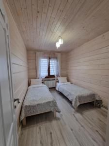 two beds in a room with wooden walls at КОТТЕДЖ У МОРЯ in Chornomorsk