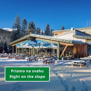 a building with picnic tables in the snow at Strachan Family Jasná in Belá