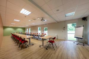 ein Konferenzraum mit Tischen und Stühlen und einer Leinwand in der Unterkunft Ethic Etapes Lac De Maine in Angers