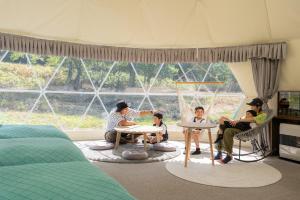 eine Gruppe von Personen, die in einem Zimmer mit einem Zelt sitzen in der Unterkunft Glamping TOMAMU in Tomamu