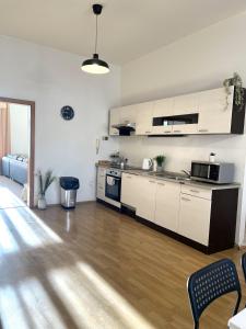 a kitchen with white cabinets and a wooden floor at Apartment Olivia - Old Town, AC in Bratislava +8 photos