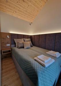 a bedroom with a bed with two towels on it at Nowe Domki Deluxe z widokiem na zatokę z basenem i sauną in Osłonino