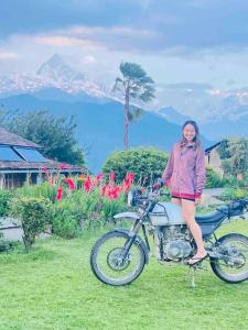 a woman sitting on a motorcycle in the grass at Annapurna Eco Village in Pokhara
