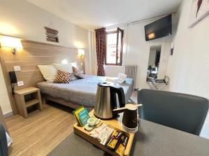 um quarto de hotel com uma cama e uma mesa com comodidades para preparar café em Hôtel Du Cheval Blanc em Barcelonnette