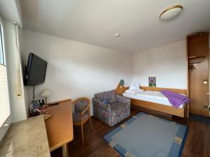 ein Hotelzimmer mit einem Bett und einem Stuhl in der Unterkunft Hotel Pension Heidi in Dobel