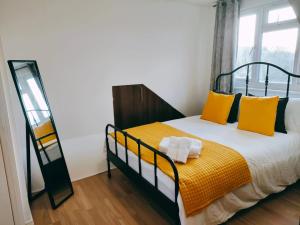 ein Schlafzimmer mit einem Bett mit gelben Kissen und einem Spiegel in der Unterkunft Iris Apartment in Wembley in London