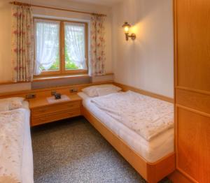 - une petite chambre avec 2 lits et une fenêtre dans l'établissement Gästehaus Manfred, à Mittenwald