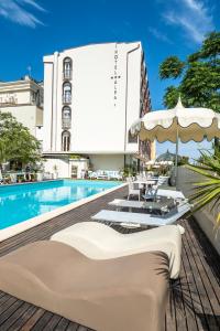 una piscina con sedie e ombrelloni accanto a un edificio di Hotel Alba a Misano Adriatico