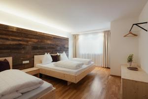 a bedroom with two beds and a wooden wall at La Residence in Molini di Tures