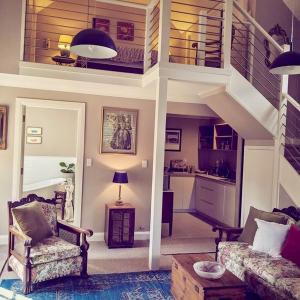 una sala de estar con una escalera con sillas y una mesa. en Bundanoon Bijou Southern Highlands Accommodation, en Bundanoon