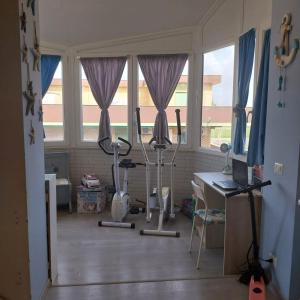 a room with windows and a treadmill and a desk at Appartamento da alessandra in Torvaianica