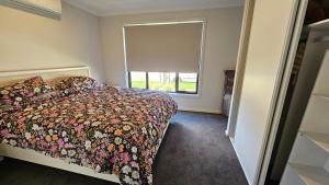 a bedroom with a bed with a floral bedspread and a window at Private Master Bedroom with Ensuite in Officer in Officer