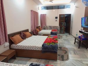a living room with two beds and a tv at Aashirwad Residency Premium Vila in Ujjain