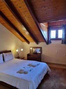 a bedroom with a large bed with a wooden ceiling at Kalavrita Krinides Apartment and Attics in Kalavrita