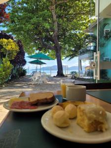 dos platos de desayuno en una mesa con una playa en Pousada Vila Verde, en Porto Belo