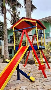 um parque infantil com uma estrutura de brincar colorida em frente a um edifício em Pousada Vila Verde em Porto Belo