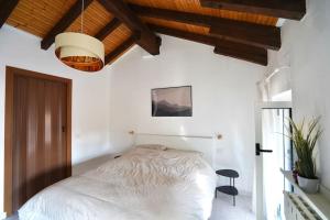 Schlafzimmer mit einem weißen Bett und Holzdecken in der Unterkunft Comodo Bilocale MXP-RHO/LIUC - Casa Deutzia in Castellanza