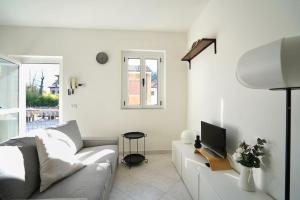 ein weißes Wohnzimmer mit einem Sofa und einem TV in der Unterkunft Comodo Bilocale MXP-RHO/LIUC - Casa Deutzia in Castellanza
