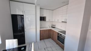 a kitchen with white cabinets and a black refrigerator at Alexander Home in Gotse Delchev